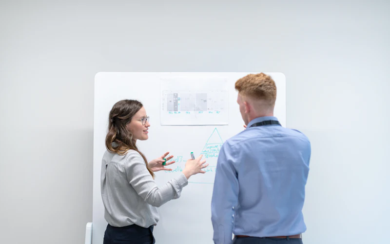 Deux personnes qui travaillent devant un tableau blanc