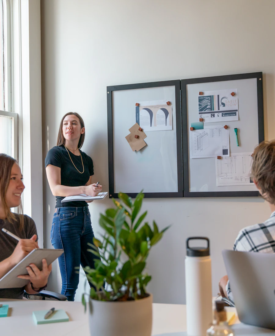 Réunion de travail dans un bureau lumineux, devant un tableau couvert de documents
